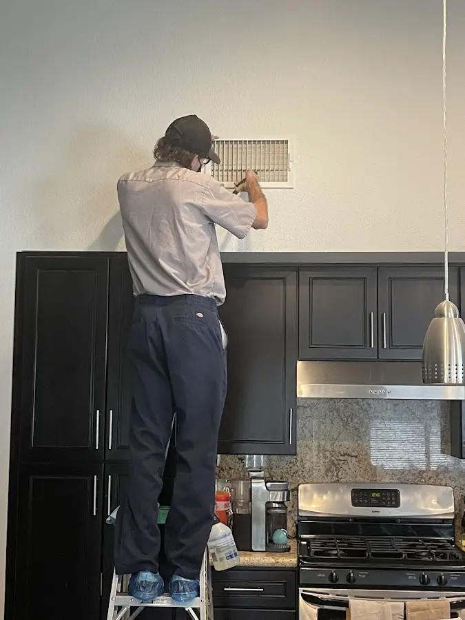 Technician inspecting an air vent during HVAC service in Greer